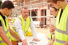 Young people listening to an employer talk on a construction site.