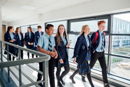 Young people wearing school uniform walking along school corridor.