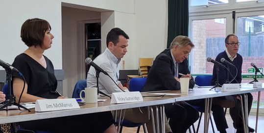 Image of panel speakers at a table with microphones