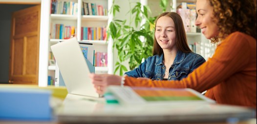 Girl and youth support worker sitting looking at a computer