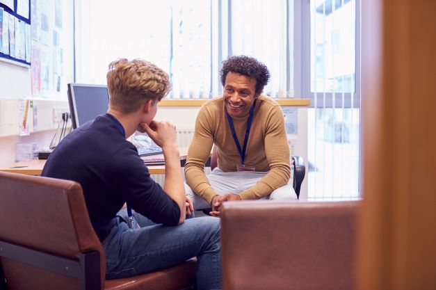 Youth worker and young person talking and smiling in an office.