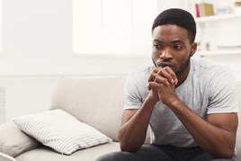 Young person sitting with hands clenched and looking worried.