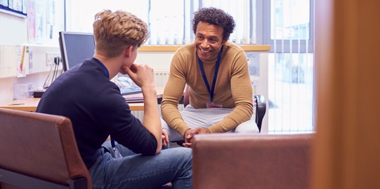 A man mentoring  and chatting to a young man