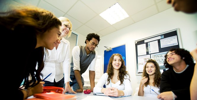 A group of young people sat around a table having a discussion.