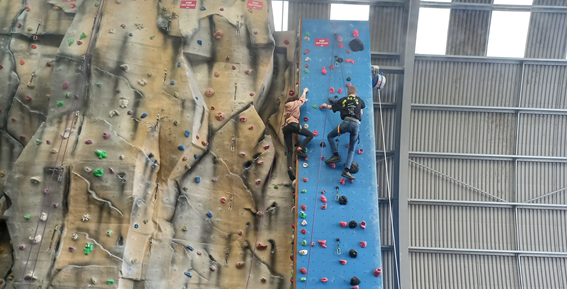 Two young people climbing on a climbing wall.