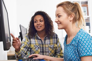 Young person and youth worker looking at a computer together.