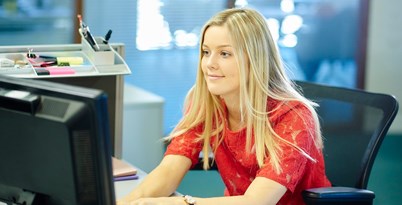 Young woman sitting at a work station in an office smiling