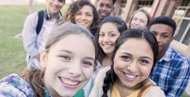 Group of young people taking a selfie and smiling at camera.