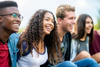 Group of young people sitting in a row smiling.