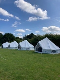 Line of tents set up on the grass at Hudnall Park.