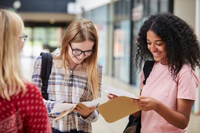 Young people opening their exam results and smiling.