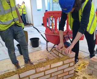 A young person practising how to build a wall at the Waltham Cross Young People's Centre.